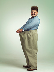 Image showing Happy man, plus size and weight loss with pants for measurement or waist on a studio background. Male person with smile for healthy diet, nutrition and oversize in fashion or clothing on mockup space