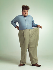 Image showing Happy man, portrait and plus size with pants for waist, weight loss or measurement on a studio background. Male person with smile for healthy diet, obesity or overweight clothing on mockup space