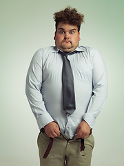 Image showing Man, portrait and shocked with plus size pants or big waist in obesity, overweight or measurement on a studio background. Young male person struggling to fit clothing with body fat or chubby stomach