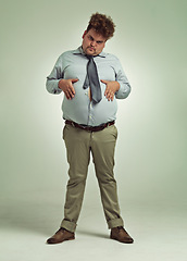 Image showing Business man, portrait and plus size with stomach gesture, joke and silly in a studio with funny face. Goofy, employee and office fashion with fun and modern clothing with green background and humor