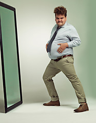 Image showing Funny, portrait and man happy with mirror, plus size and overweight with hand on stomach or abdomen. Confident, male person and guy with double chin from fat in body, unique and crazy in studio