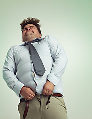 Image showing Frustrated man, pants and plus size with big waist in obesity or overweight on a studio background. Young male person struggling to fit on clothing with body fat or chubby stomach on mockup space