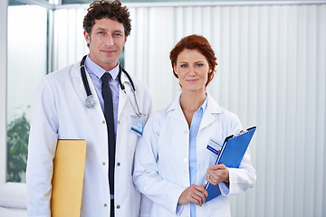 Image showing Doctors, man and woman with smile in portrait for team, partnership and documents with pride for healthcare. Medic employees, people and clipboard in clinic for collaboration, wellness and services