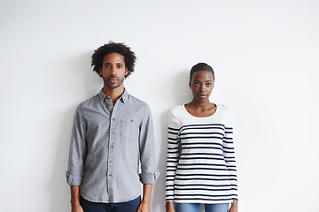 Image showing Couple, serious and portrait by white wall in fashion with confidence, casual style and model aesthetic. Black woman, and face of man with trendy apparel, edgy clothes and pride with calm expression