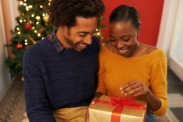 Image showing Christmas, present and black couple giving a box or opening surprise on festive holiday or vacation with happiness. Excited, woman and man offer a gift in home with love and kindness in marriage