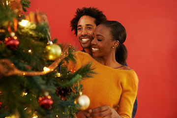 Image showing Couple, Christmas and tree decoration in home with happiness for vacation celebration, giving or bonding. Man, woman and smile with lighting for winter season for family event, embrace or lounge