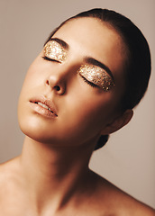Image showing Woman, face and gold glitter eyeshadow for beauty, cosmetology and glamour with cosmetics on beige background. Makeup, elegance and fashion model in studio, art or creativity with shimmer and glow