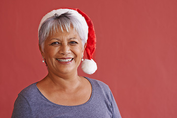 Image showing Portrait, smile and Christmas hat with senior woman, retirement and happiness on red studio background. Face, old person and elderly lady with joy or Xmas with celebration, cheerful or festive season