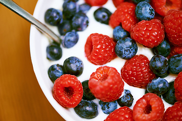 Image showing Raspberry, berries and bowl with yogurt, closeup and blueberry for organic snack. Food, cuisine and breakfast for health, wellness and diet for morning nutrition and antioxidant wellbeing in studio