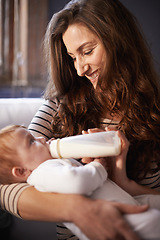 Image showing Mother, baby and milk feeding with bonding in a family home with love, support and care together. Smile, relax and bottle for youth development and growth with mom and happy on a living room sofa