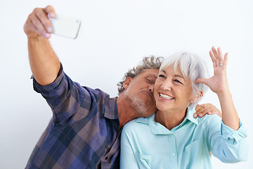 Image showing Old couple, kiss in selfie and happy together for social media post, memory and love with fun on white background. Affection, trust or loyalty with people in marriage, smile in picture and mobile app