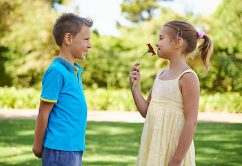 Image showing Children, friends and flower gift or outdoor connection with love kindness or young care, bonding or innocent. Boy, girl and smile at backyard garden for smell plant or summer holiday, play or park