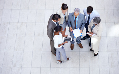 Image showing Documents, tablet and business people in discussion in lobby of office in collaboration. Paperwork, digital technology and high angle of professional financial advisors in meeting for teamwork.