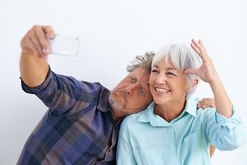 Image showing Old couple, funny face in selfie and happy together for social media post, memory and love with fun on white background. Crazy, silly or goofy with people in marriage, smile in picture and mobile app