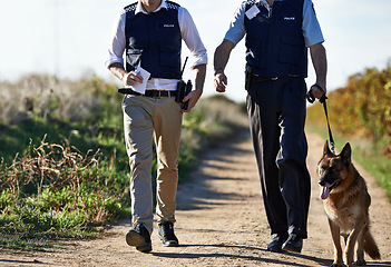 Image showing Policeman, dog and walk in field for search in crime scene or robbery for evidence, safety and law enforcement. Detective, investigation and uniform in outdoor work at countryside with gravel road