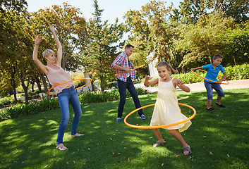 Image showing Parents, kids and hula hoop in park for playing, child development and motor skills outdoor. Children, son and daughter with mom and dad in nature for leisure, family time and bonding with smile