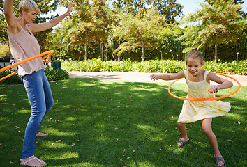 Image showing Mother, child and hula hoop for outdoor fun in backyard garden for parenting bonding, summer or holiday vacation. Woman, daughter and recreation connection on grass for playing, carefree or happy