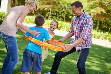 Image showing Parents, children and hula hoop in park as family, playing and bonding with motor skills outdoor. Kids, son and daughter with mother and father in nature for leisure, childhood development with smile