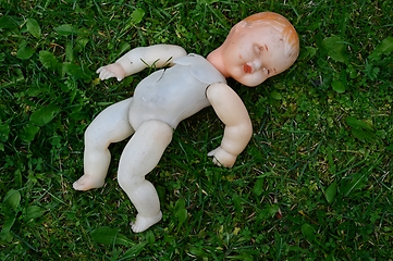 Image showing old broken doll on a grass