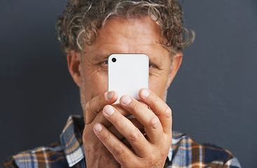 Image showing Mature, man and capture a photo with phone in studio and learning about photography on dark background. Smartphone, recording or filming a video for post online to social media for memory of picture