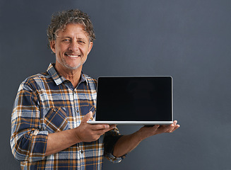 Image showing Laptop, screen and portrait of mature man in studio and learning about technology on dark background. Advertising, computer and mockup with online post to social media and search internet for news