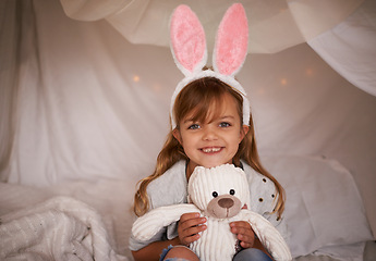 Image showing Girl, child and bunny ears with teddy bear, soft toys and playing in fort for camping and fun at family home. Happiness, innocent and kid with stuffed animal, games for Easter and joy in childhood