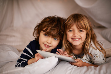 Image showing Tablet, blanket fort and portrait of kids relaxing, bonding and playing together at home. Happy, smile and young girl and boy children siblings laying in tent for fun sleepover in bedroom at house.
