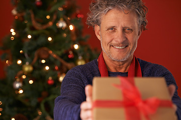 Image showing Senior man, portrait and Christmas tree with gift box for present, giving or December holiday at home. Happy male person with smile for wrapped container, festive season or ribbon of Santa at house