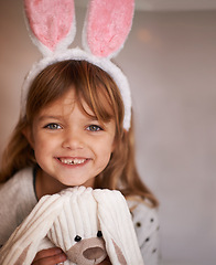 Image showing Girl, kid and bunny ears with teddy bear in portrait, soft toys and playing with smile and fun at family home. Happiness, innocent and child with stuffed animal, games for Easter and childhood