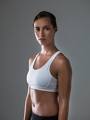 Image showing Woman, serious in portrait and confident for fitness, strong and determined with sweat from workout on grey background. Body, endurance and athlete for sports, exercise with pride and power in studio