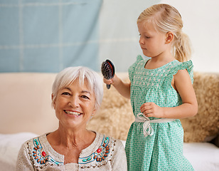 Image showing Home, hair brush and grandmother with girl for smile in bonding to play for child development or growth. Portrait, sofa and kid in happiness at living room for joy or fun, relax and laugh as family