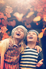 Image showing Leaves, sun and happy children in autumn season, nature and outdoors in forest. Smile, joy and wonder with falling fall foliage in wood, brother and sister in park for entertainment with lens flare