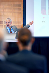 Image showing Senior, businessman and boss with presentation on projector for meeting, seminar or conference at office. Man spokesperson, CEO or speaker talking on podium to group or corporate audience at workshop