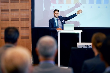 Image showing Business man, podium and presentation, pointing at projector screen at conference or workshop with laptop for PPT. Corporate training, seminar and speaker with info, audience and professional speech