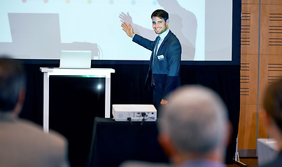 Image showing Business man, podium and presentation, point at projector screen at conference or workshop with laptop for PPT. Corporate training, seminar and speaker with info, audience and professional speech