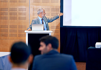 Image showing Senior, businessman and leader with presentation on projector for meeting, seminar or conference at office. Man spokesperson, CEO or speaker talking on podium to group, corporate audience or workshop