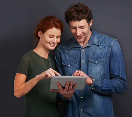 Image showing Happy couple, typing and communication with tablet for research or networking on a dark studio background. Young man and woman with smile on technology for online search, browsing or scrolling on app