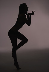 Image showing Dancer, woman and silhouette with beauty, body care and sensual on a dark studio background. Person, profile and model with shadow figure and seductive with wellness and natural pose with slim girl