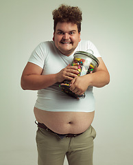 Image showing Candy, crazy and portrait of plus size man on white background for snacks, sweets and dessert in container. Comic, funny and isolated person with glass jar for unhealthy diet and sugar in studio