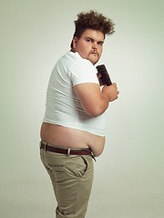 Image showing Chocolate, portrait and plus size man with junk food, dessert and candy in a studio. Funny, sweet and unhealthy snack for eating with greed gesture and hungry male person with green background