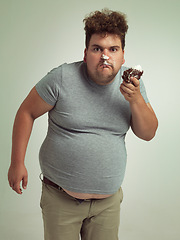Image showing Plus size, eating and portrait of man with cake in studio for unhealthy, sugar and sweet snack. Greedy, food and male person with messy slice of chocolate dessert isolated by gray background.