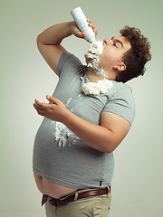 Image showing Sweet, dessert and man with whipped cream for eating in studio background, addiction and unhealthy for plus size male person. Guy, health problem and risk for diabetes with sugar and cholesterol