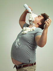 Image showing Plus size, eating and man with cream in studio for unhealthy, sugar and sweet snack or dessert. Messy, greedy and hungry plus size male person enjoying whipped dairy product by gray background.