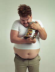 Image showing Candy, jar and crazy plus size man in studio for snacks, sweets and dessert in container. Comic, funny and isolated silly person with glass for unhealthy diet, sugar and treats on white background