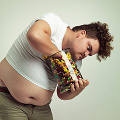 Image showing Candy, jar and man in on studio background crazy for luxury snack, sweets or dessert in container. Comic, facial expression and isolated and plus size person with glass for unhealthy diet and sugar