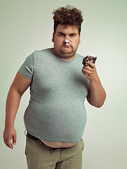 Image showing Chocolate cake, portrait and plus size man with grumpy, dessert and candy in a studio. Silly, sweet and unhealthy snack for eating with junk food and hungry person with green background with joke