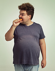 Image showing Plus size, diet and man eating carrot for nutrition, health benefit and wellness in studio by white background. Weight loss, vegetable and hungry male person for detox, wellbeing and vegan food