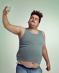 Image showing Selfie, fashion and plus size man in studio posing with casual, trendy and cool outfit with stomach. Style, serious and crazy male person with photography picture isolated by gray background.