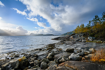 Image showing Majestic coastal scenery with sunlit rocks and dramatic sky at d