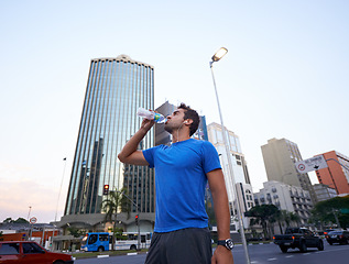 Image showing Hydration, break and man drinking water in city for exercise, running or marathon with bottle. Thirsty, workout and male athlete resting for body recovery, fatigue or summer training in urban town